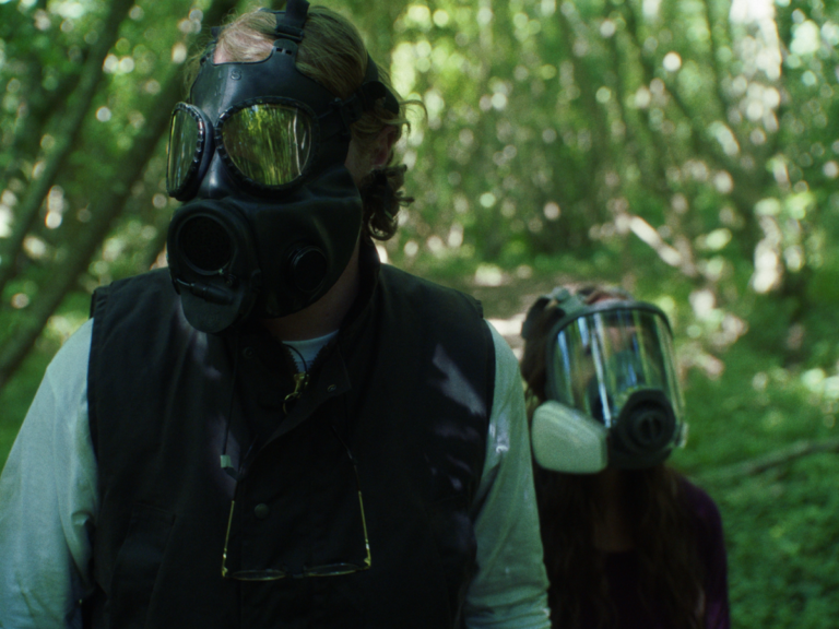 Chester and Mel wear full-face respirators in the woods in Littermates.